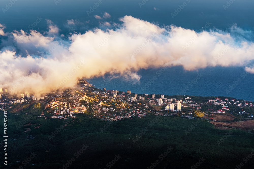 Fototapeta premium A magical view in the mountains above the clouds. Peak AI-Petri in the Crimea in the evening, when the sun sets behind the mountain