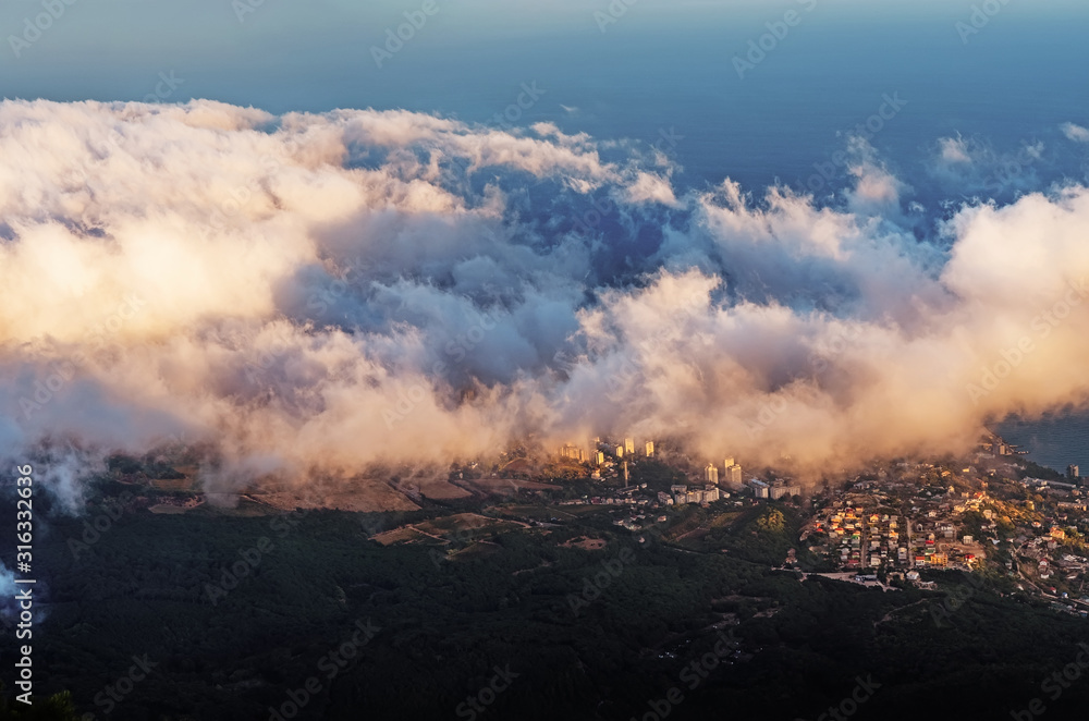 Fototapeta premium A magical view in the mountains above the clouds. Peak AI-Petri in the Crimea in the evening, when the sun sets behind the mountain