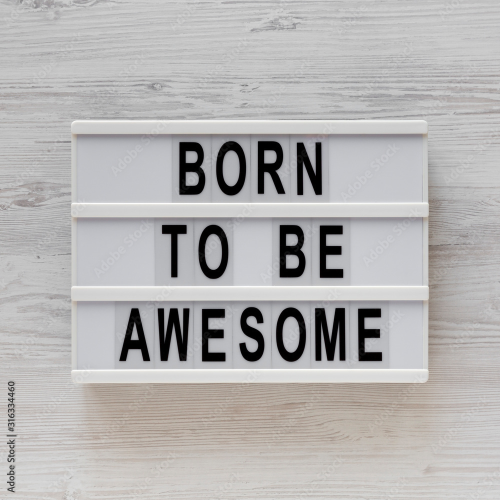 'Born to be awesome' words on a modern board on a white wooden background, top view. Overhead, from above, flat lay. 'Born to be awesome' words on a modern board on a white wooden background, top view. Overhead, from above, flat lay.