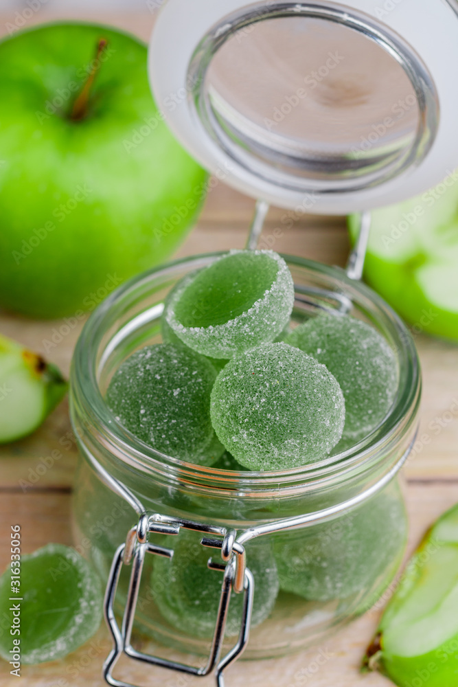 Apple green marmalade candy in sugar in a glass jar. Delicious homemade jelly sweets. Healthy dessert for gourmets. Selective focus Apple green marmalade candy in sugar in a glass jar. Delicious homemade jelly sweets. Healthy dessert for gourmets. Selective focus