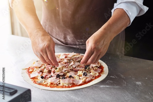 Fototapeta pizza in box chef is decorating pizza homemade with fried bacon 