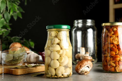 Glass jars of pickled mushrooms on light grey table