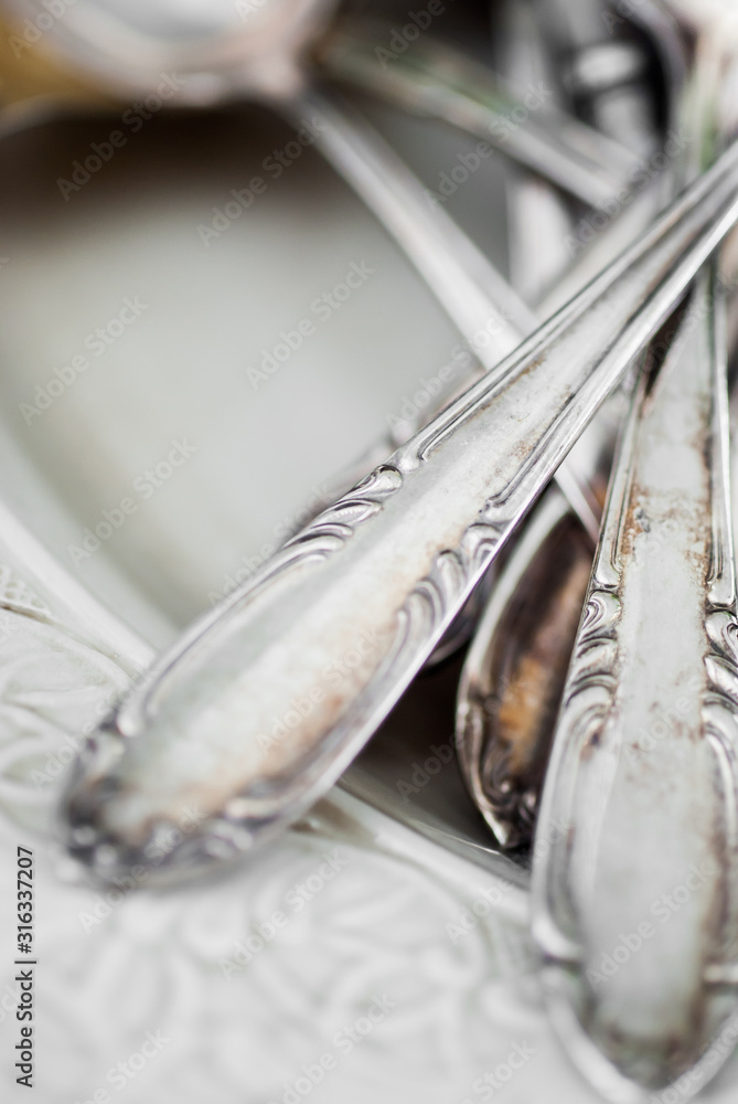 Old silver cutlery handles on an off-white, patterned serving plate.