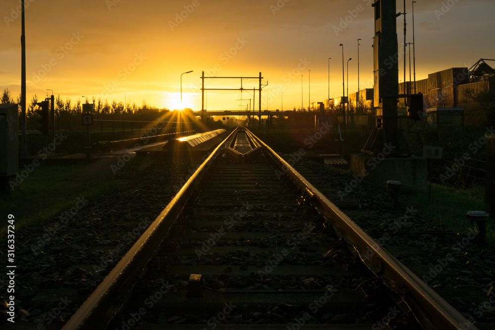 Railroad track vanishing in the distance at sunrise