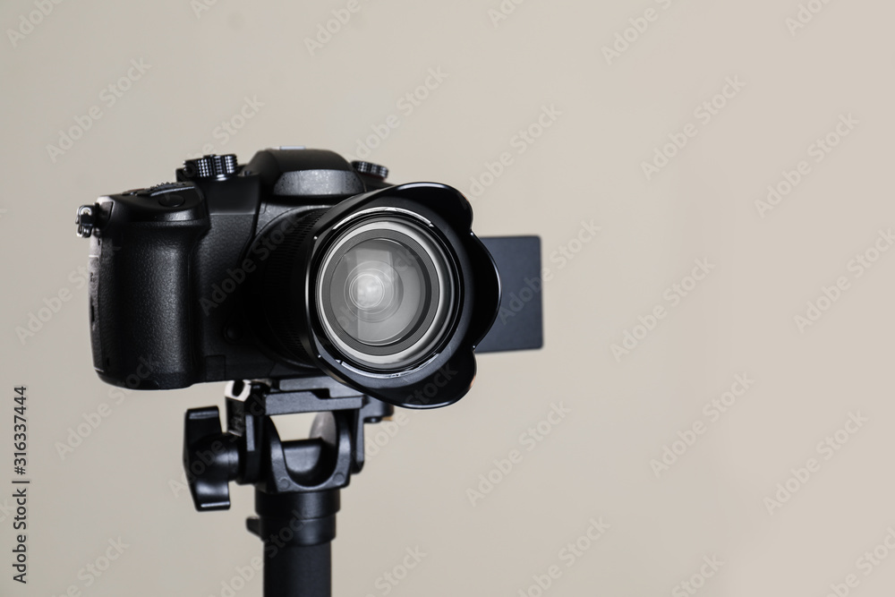 Modern professional video camera on beige background