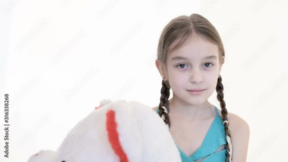 Beautiful girl with pigtails in blue dress hugs Big Bear on a white background. Beautiful girl with pigtails in blue dress hugs Big Bear on a white background.