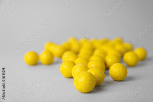 Delicious lemon chewing gums on light grey background, closeup