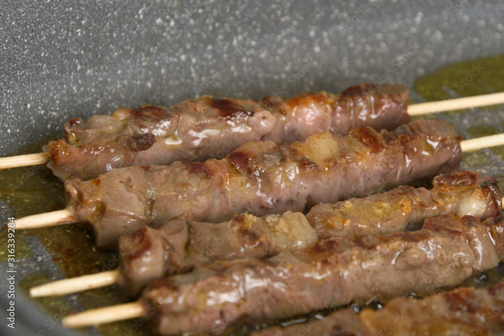 Selective focus. Cooked raw meat skewers is a pan, side view. Close up