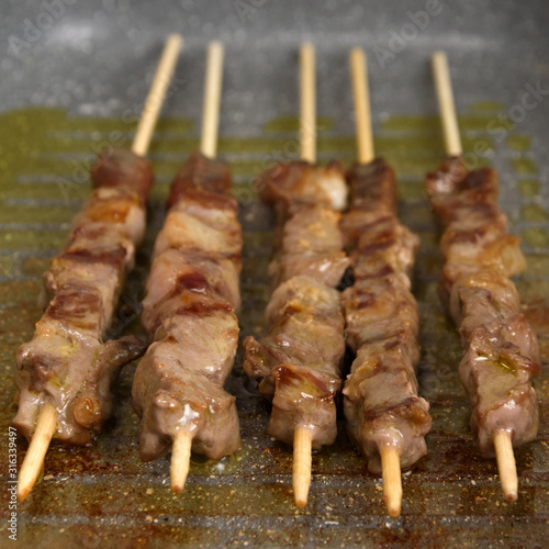 Selective focus. Cooked raw meat skewers is a pan, in perspective. Close up
