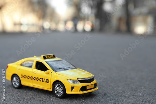 Fotografie, Obraz Yellow taxi car model on city street. Space for text