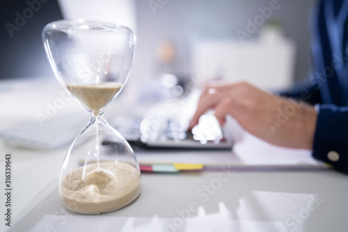 Businessperson's Hand Calculating Invoice In Office