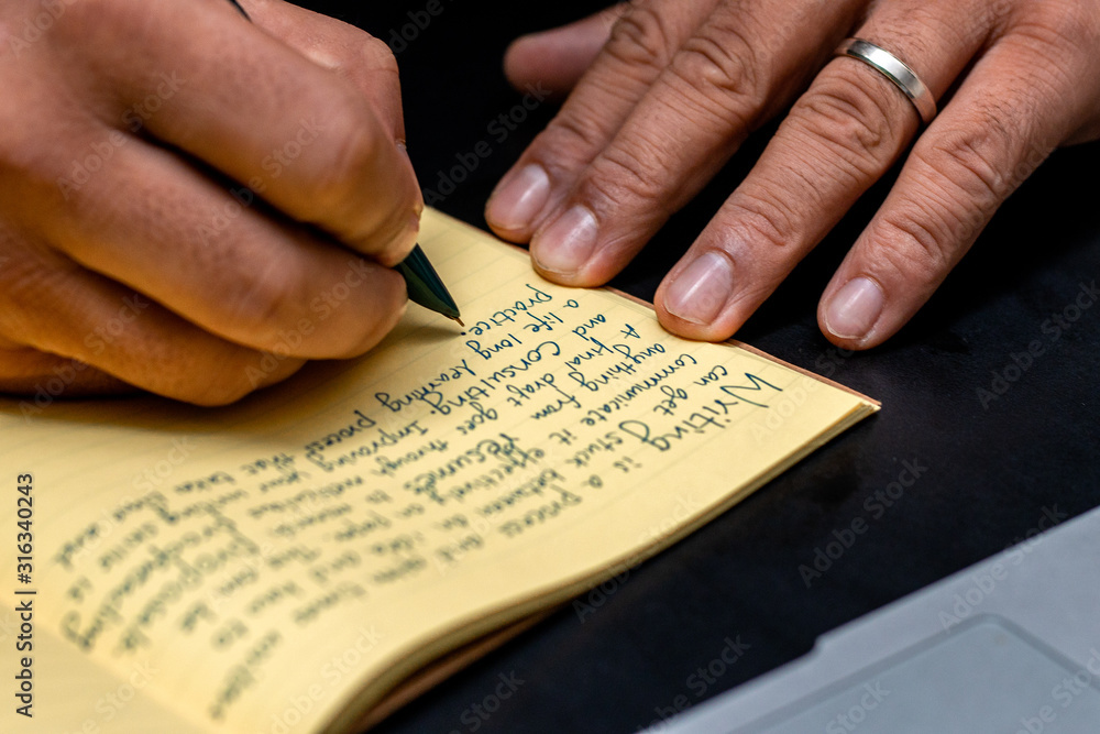 Fototapeta premium Hand of a young businessman taking notes with a fountain pen on a notecopy. Student learning online. Blogger. selective focus