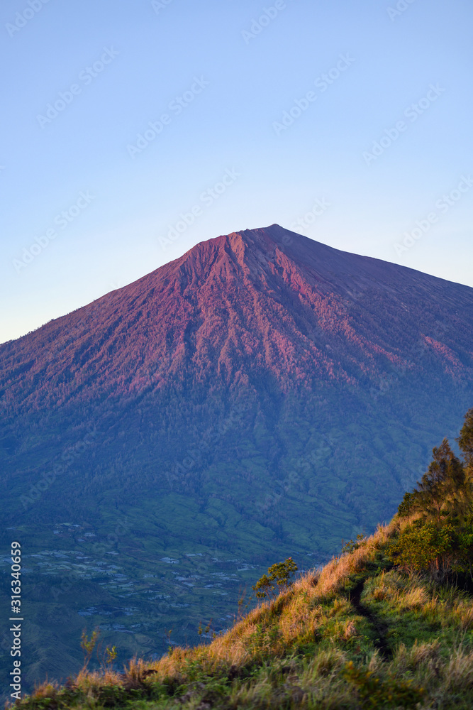 (Selective focus) Stunning view of the Mount Rinjani illuminated by a beautiful sunrise. Mount Rinjani (Gunung Rinjani) is an active volcano and the second highest mountain in Indonesia.