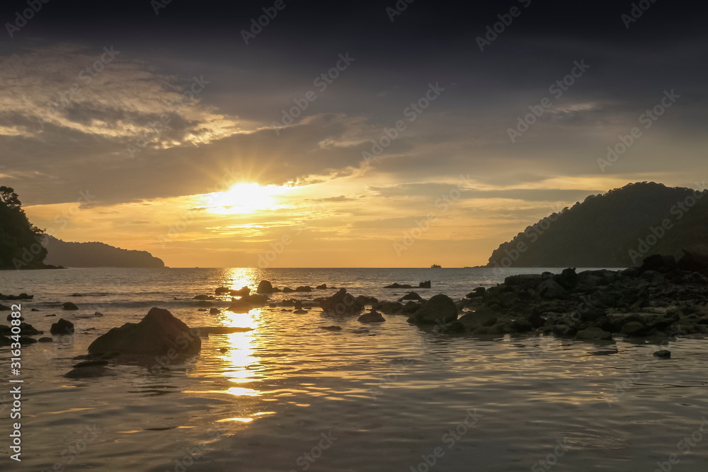 view seaside evening of many arch rocks in the sea with yellow sun light and cloudy sky background, sunset at Khao Chong Kad, Mu Ko Surin island, Phang Nga, southern of Thailand.