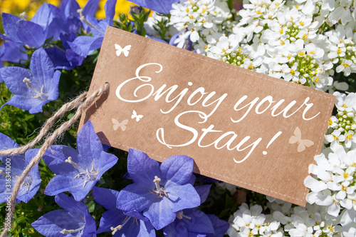Paper card board with flowers and plants with message Enjoy your stay