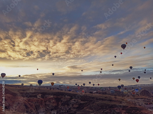 Colorful hot air balloons flying at the sunrise with rocky landscape in Cappadocia, Turkey