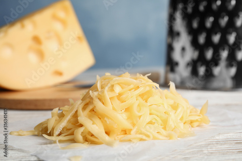 Tasty grated cheese on white wooden table, closeup