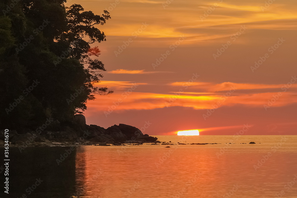 Silhouette the rocks in the sea with sun dawn and orange sky background, sunset at Chong Khao Kad, Mu Ko Surin National Park, Phang Nga, southern of Thailand.