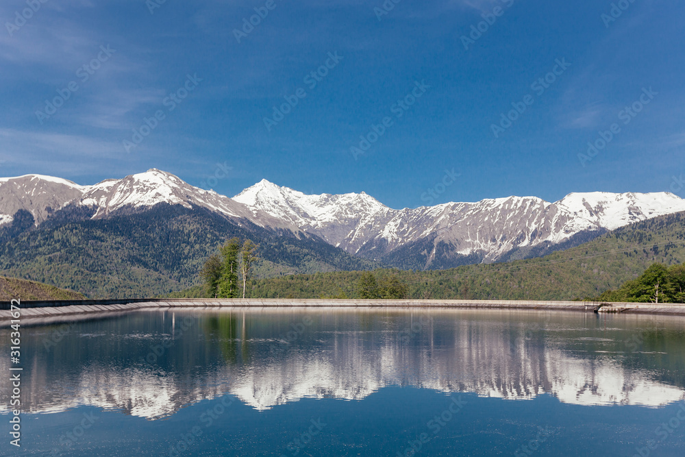 Stunning picturesque landscape of a mountain lake against the backdrop of mountains and blue sky on a sunny warm summer day. The concept of travel and nature reserves. Copyspace