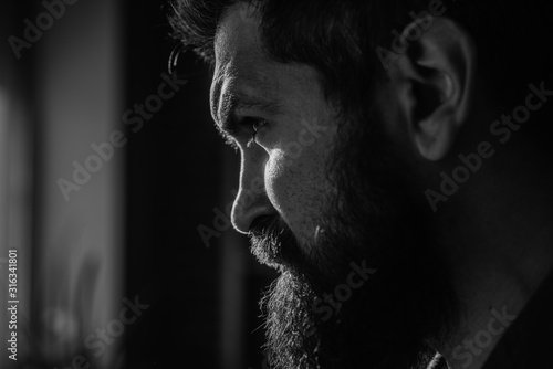 Handsome and confident. Outdoor portrait of young man with beard. Portrait of a bearded man with an intense look standing in a dark room against a black background.