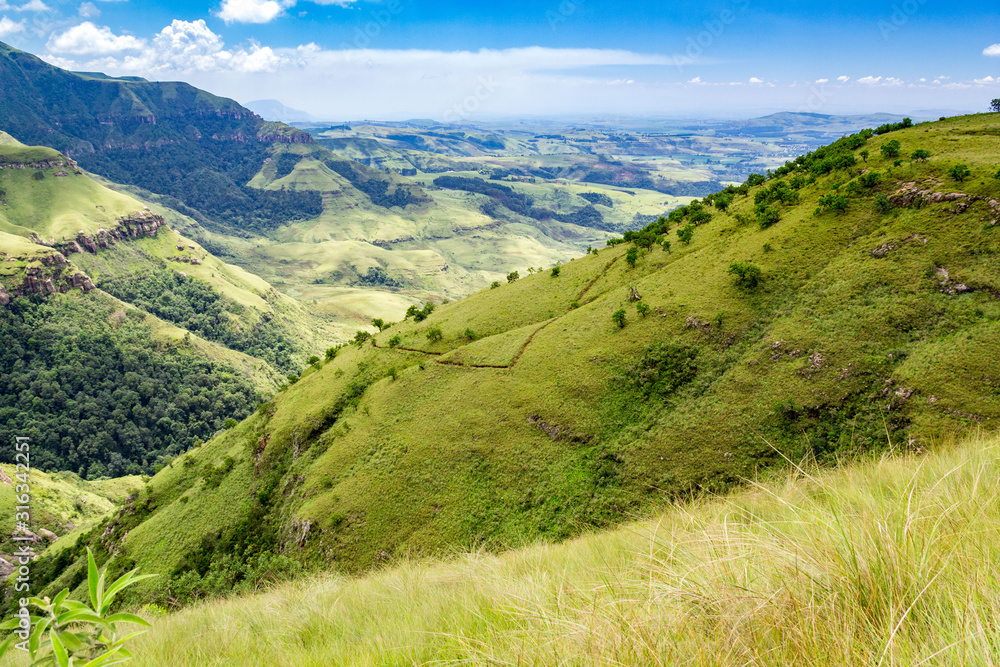 Panoramic view over steep and green mountains and bright meadows, sunny day, Drakensberg, Giants Castle Game Reserve, South Africa