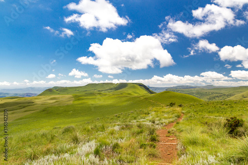 Panoramic view from a grassy plateau with a small hiking trail to soft green mountains, Giants Castle Game Reserve, Drakensberg, South Africa