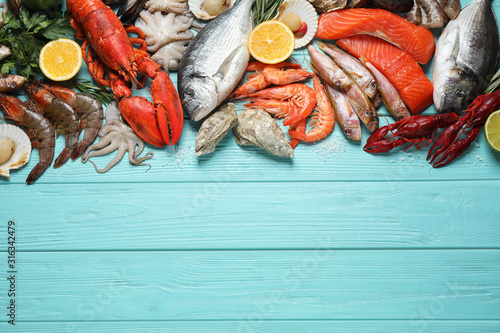 Fresh fish and different seafood on blue wooden table, flat lay. Space for text