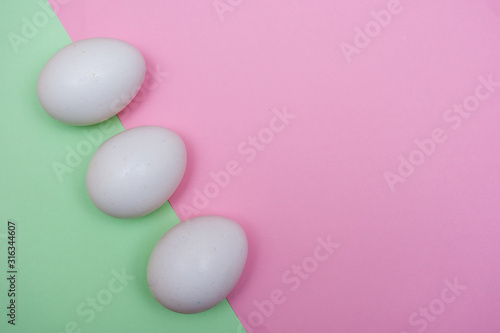 Easter holiday flat lay with white egg on a solid light green pastel background with copy space.