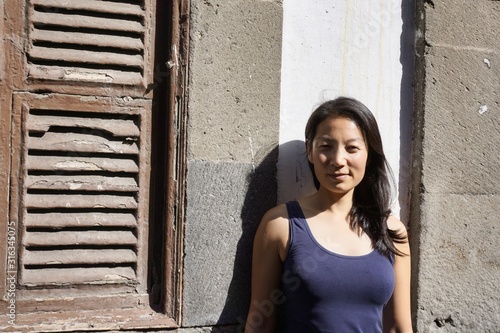 beautiful young woman on holiday in a blue top in front of an old building with shutters