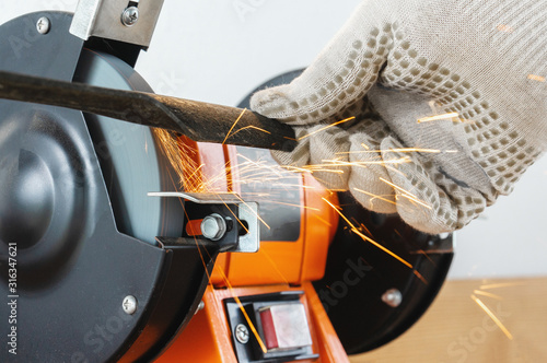 Canvas-taulu Sharpening the blade of a lawn mower with an electric sharpener