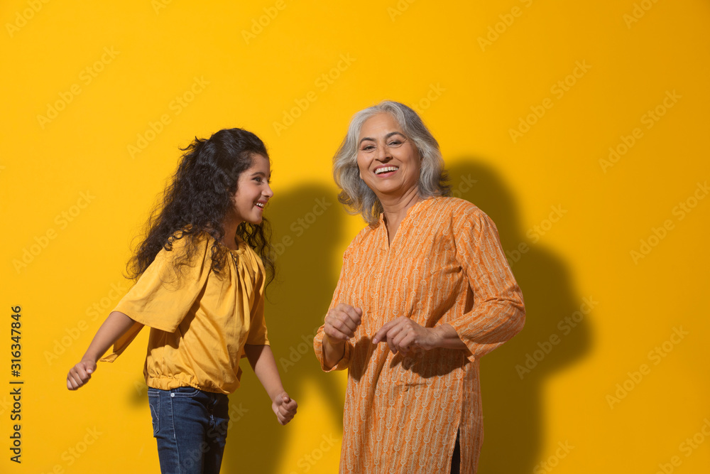 Obraz premium Portrait of a happy grandmother dancing with her grand-daughter. 