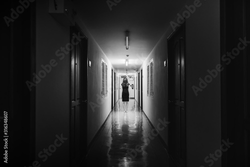 Horror photo of woman with long hair walking on corridor in white tone