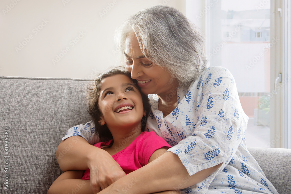 Portrait of a grand-daughter and grandmother sitting on the couch at home. Portrait of a grand-daughter and grandmother sitting on the couch at home.