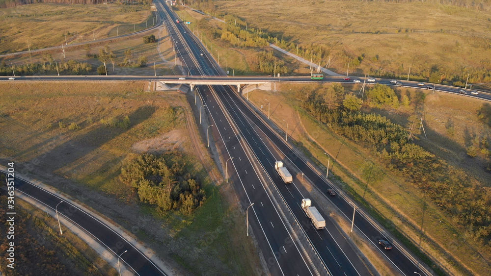 aerial view. Interchange on the intercity highway. Cars and trucks travel in different directions. Two stripes in each direction.