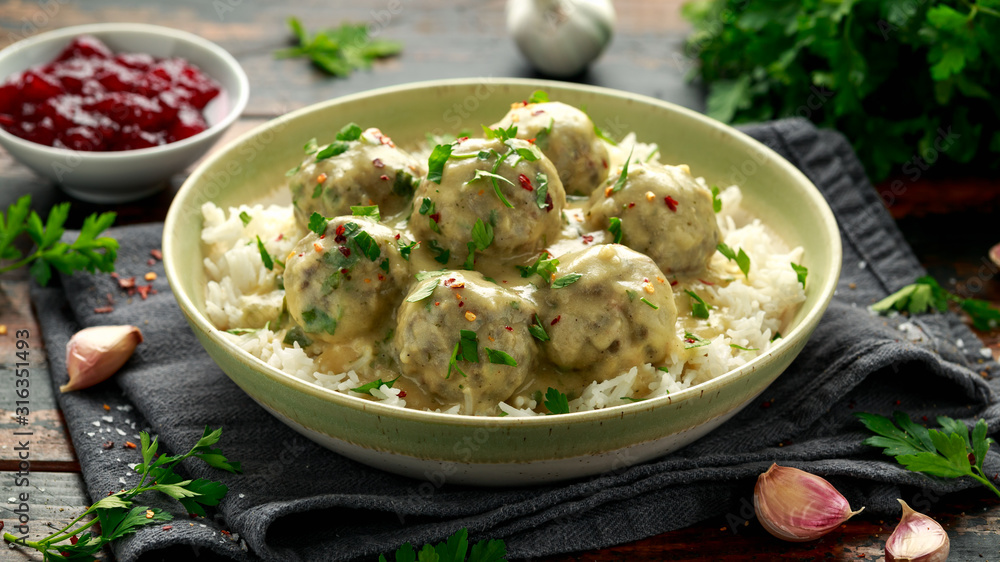 Hot Swedish meatballs with white rice and cranberry sauce on wooden table Hot Swedish meatballs with white rice and cranberry sauce on wooden table
