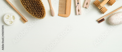 Zero waste bathroom accessories on green background. Frame border of luffa sponge, massage brush, bamboo toothbrushes, hair comb, wooden pins, handmade soap. Eco-friendly bath products, beauty and spa