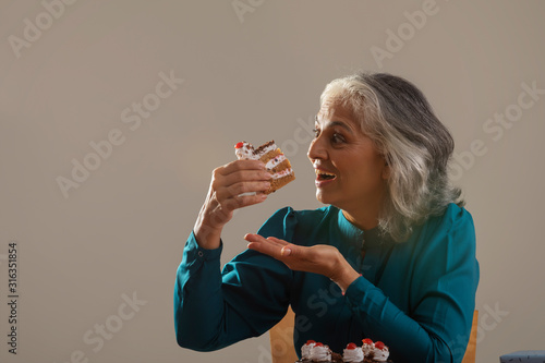 Portrait of a grandmother eating her birthday cake. (Senior) 