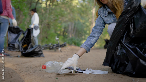 Conscious citizens arranged for cleaning the forest from household waste. Women volunteers collect rubbish in the nature and eliminate pollution. Civilized position. © kustvideo