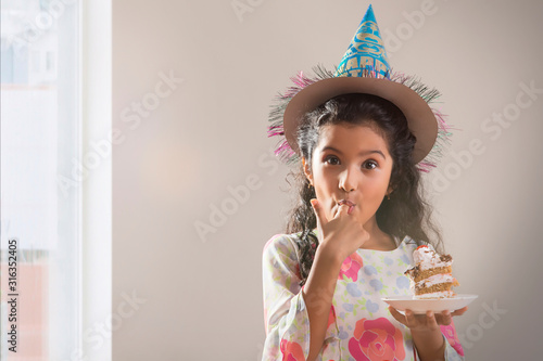 Portrait of a young girl eating her birthday cake. (Children)  	
