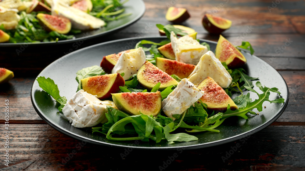 Vegetarian camembert cheese, fig and Arugula, hot rocket salad served on black plate Vegetarian camembert cheese, fig and Arugula, hot rocket salad served on black plate