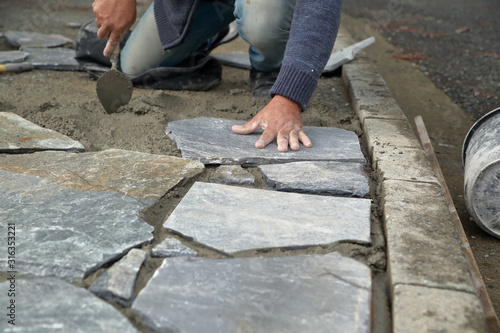 Builder  builds places sidewalk from natural stones