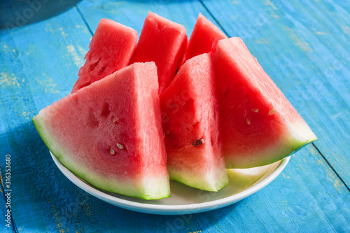 fresh sliced watermelon on plate on blue wooden table