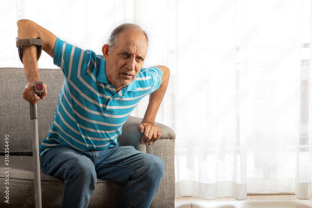 Senior man trying to stand up from couch with a Walking stick, Cane. (Health and fitness) Senior man trying to stand up from couch with a Walking stick, Cane. (Health and fitness)