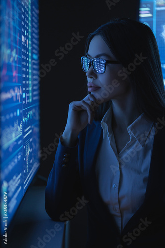 The business woman looks on a large blue screen with chart