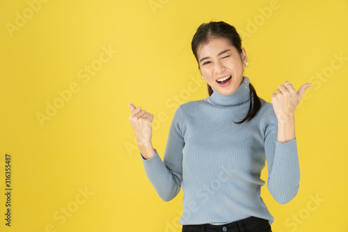 Women with thumbs pointing on both sides in the yellow background. photo