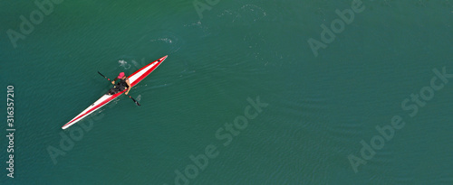 Aerial drone ultra wide photo of fit athletes practising sport kayak in tropical exotic lake with emerald water