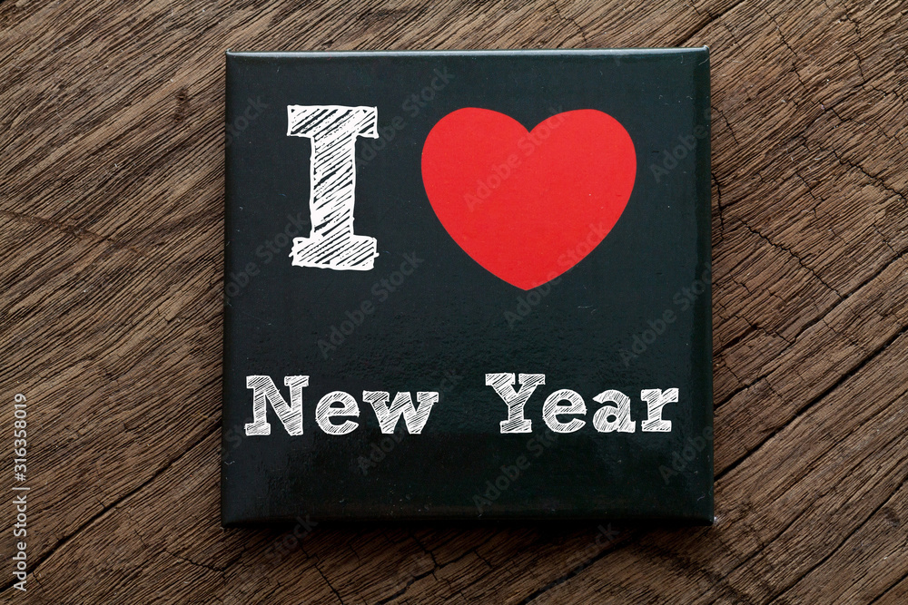 I love New Year written on black card with wood background