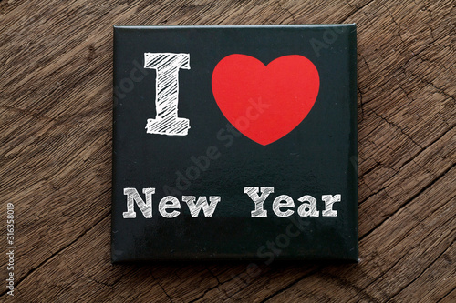 I love New Year written on black card with wood background