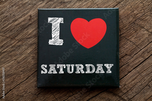 I Love Saturday written on black note with wood background