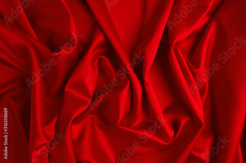 Red silk fabric lying in form of waves.